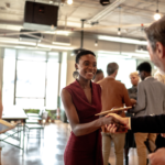 networking event - 2 people shaking hands in a room full of people