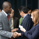 networking event where two people are shaking hands and handing out a business card